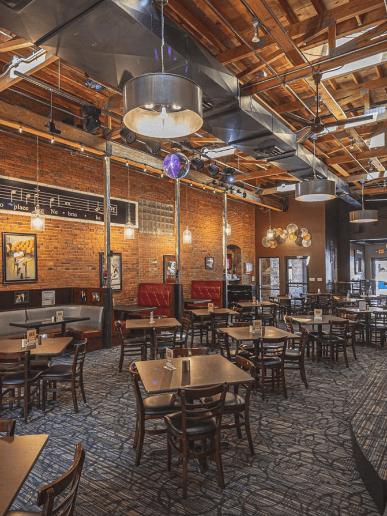 Cozy restaurant interior with exposed brick walls, modern lighting, and wooden furniture, perfect for dining and events.