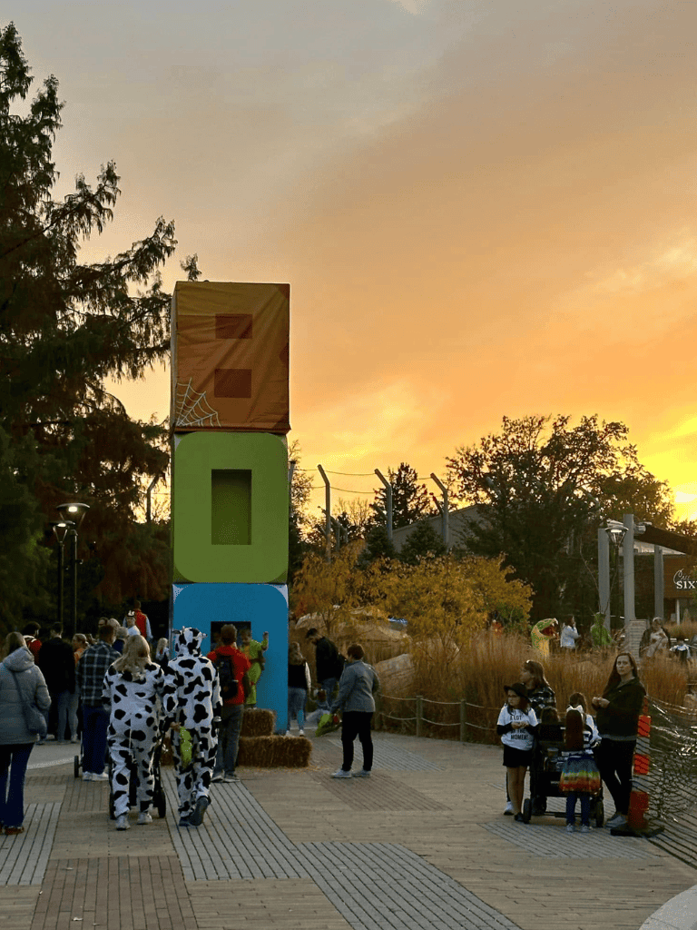 Colorful quest-themed outdoor attraction with visitors and children in costumes at sunset.