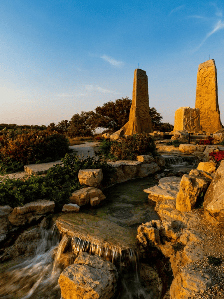 Viking sculptures and water feature at Quest for Directions outdoor park, Texas, during sunset.