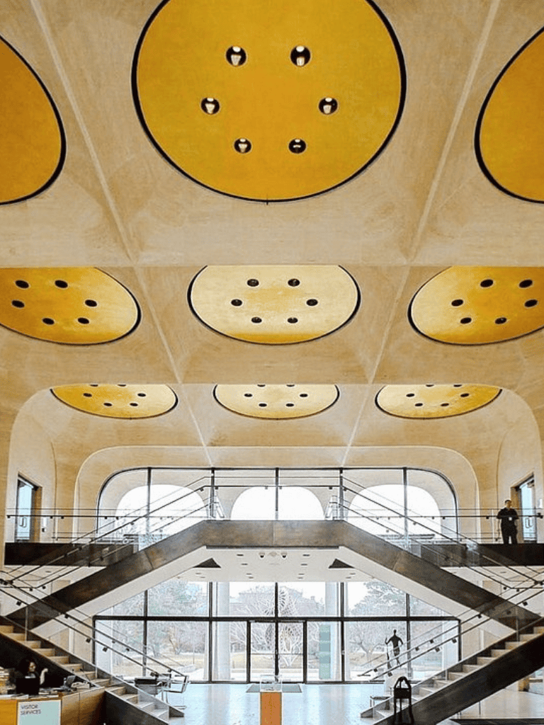 Open modern interior with unique ceiling art and large windows at Quest for Directions building.