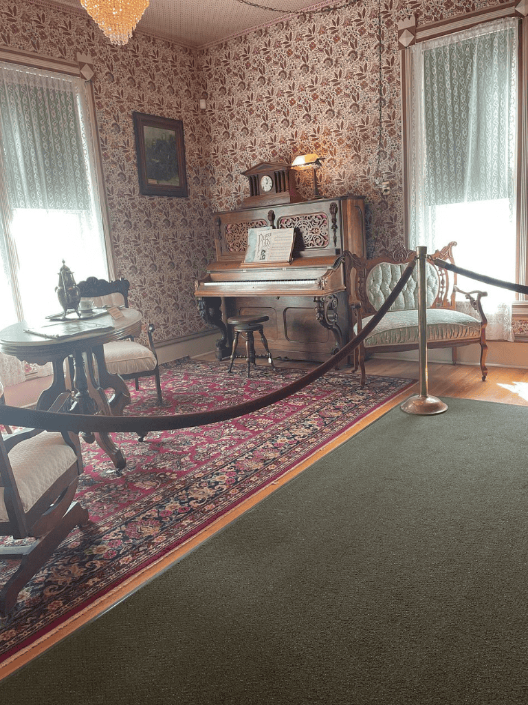 1. Vintage piano in Victorian-style living room with floral wallpaper and antique furniture.