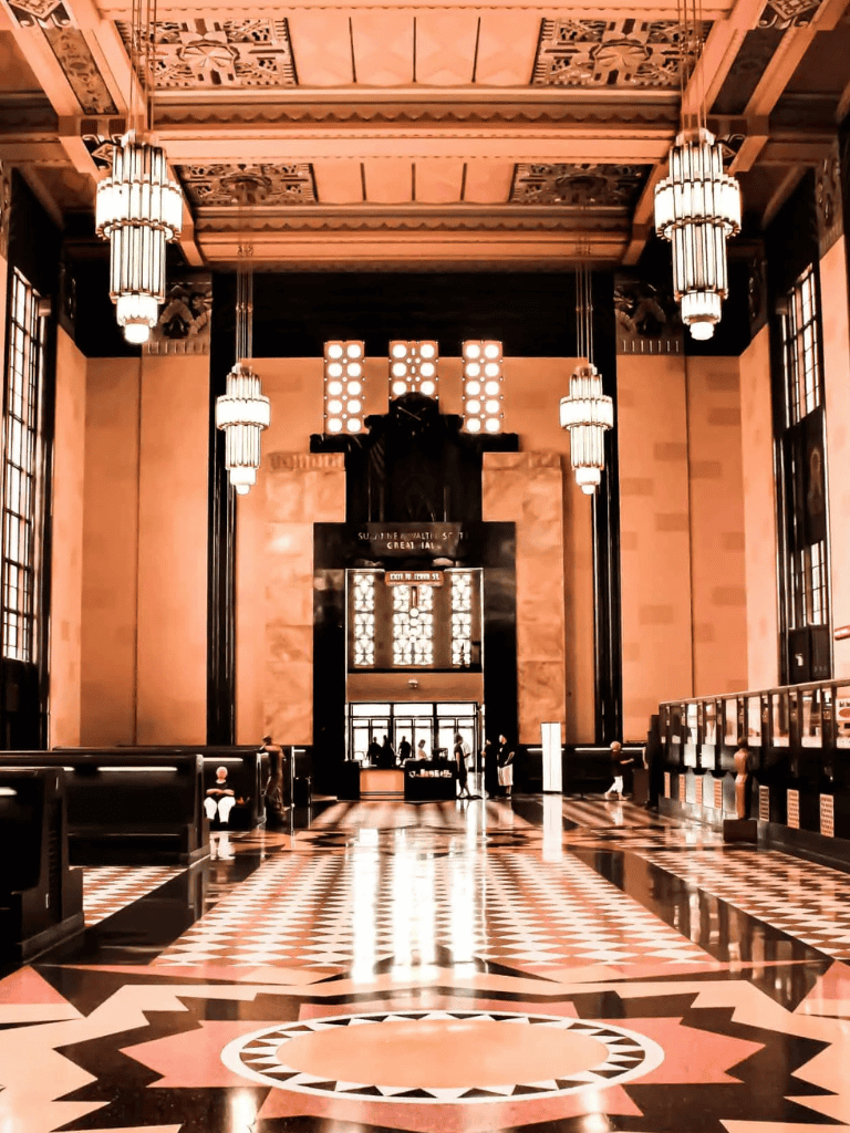 Stylish hotel lobby with art deco design, luxurious chandeliers, and intricate marble flooring.