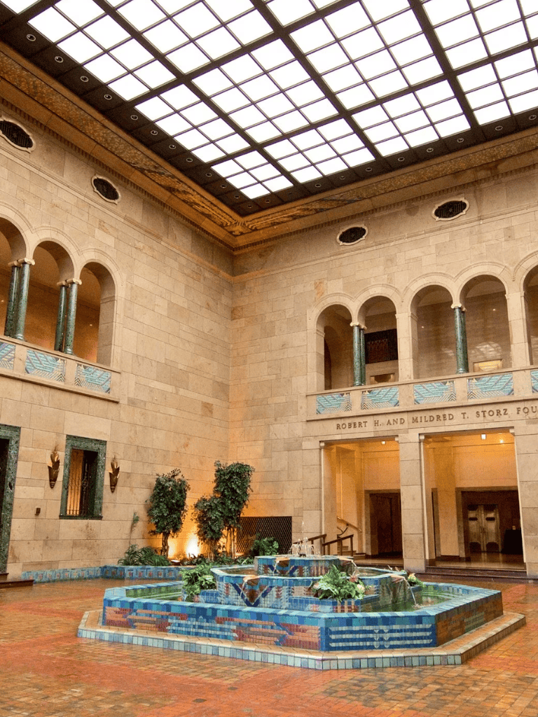 Elegant hotel lobby with fountain, stone walls, and skylight ceiling, perfect for travel planning and directions.