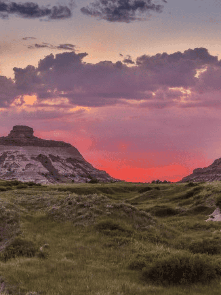 Serene sunset over rugged landscape with rock formations and lush grass, perfect for travel and adventure exploration.