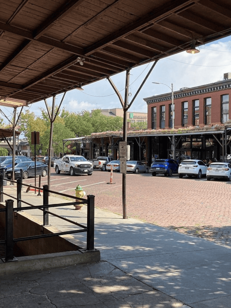 Quiet downtown street view with parked cars and historic brick building, perfect for exploring local businesses and dining.