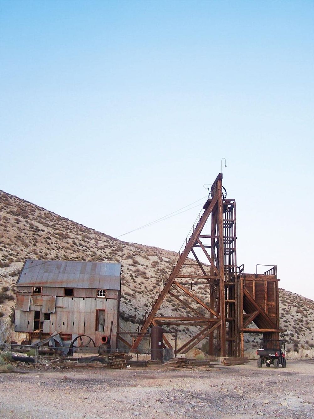 Rustic abandoned mine shaft with old wooden structures in a remote desert landscape.