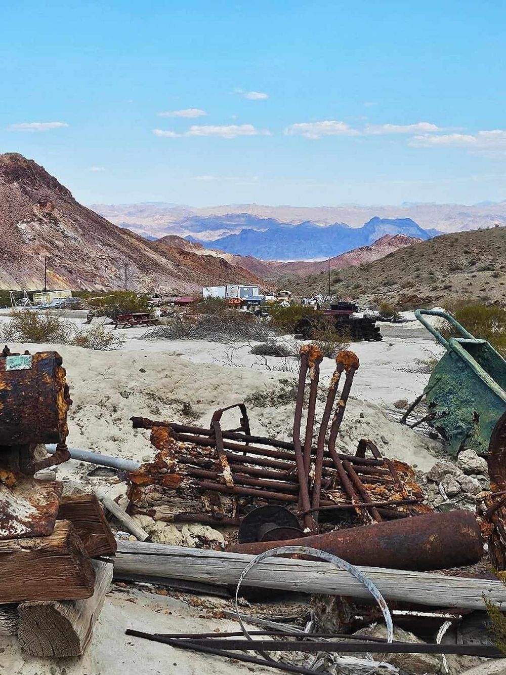 Rusty abandoned equipment in a desert landscape with mountains and a clear blue sky.