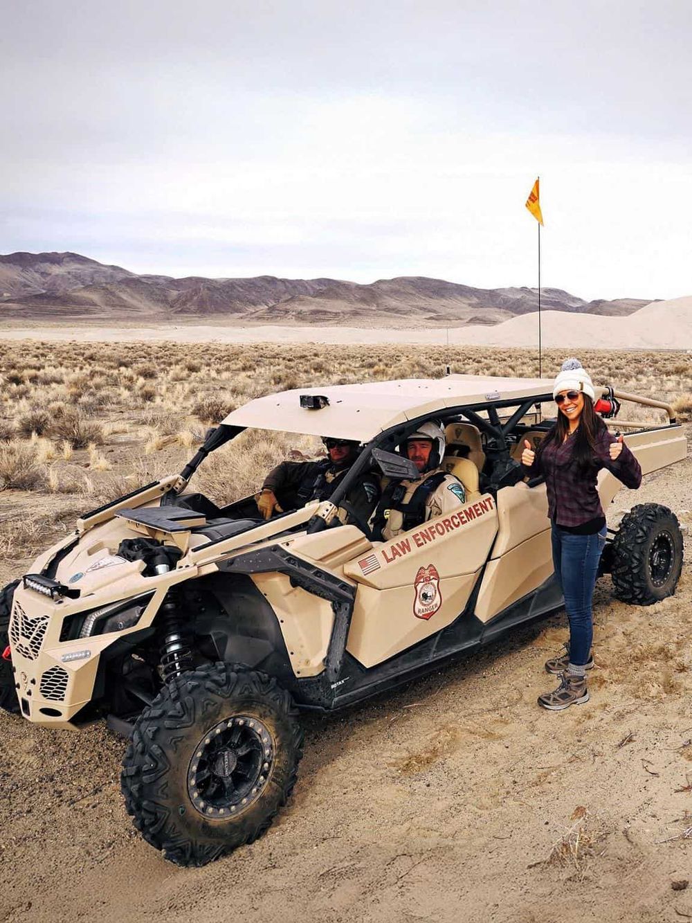 Off-road desert adventure with law enforcement vehicle and smiling woman in outdoor gear.