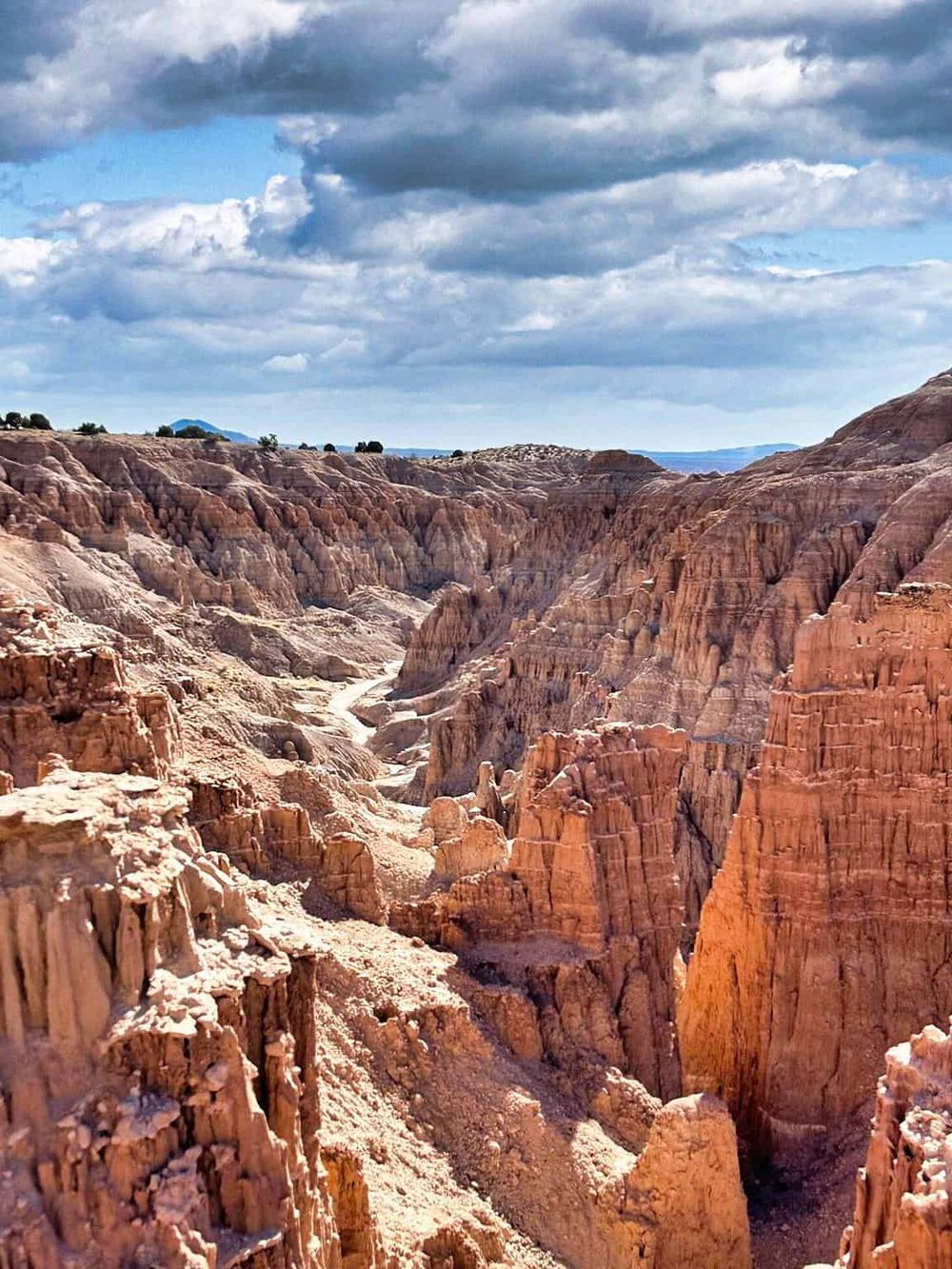 Vibrant canyon landscape with colorful rock formations and dramatic cloud-filled sky at QuestForDirections.