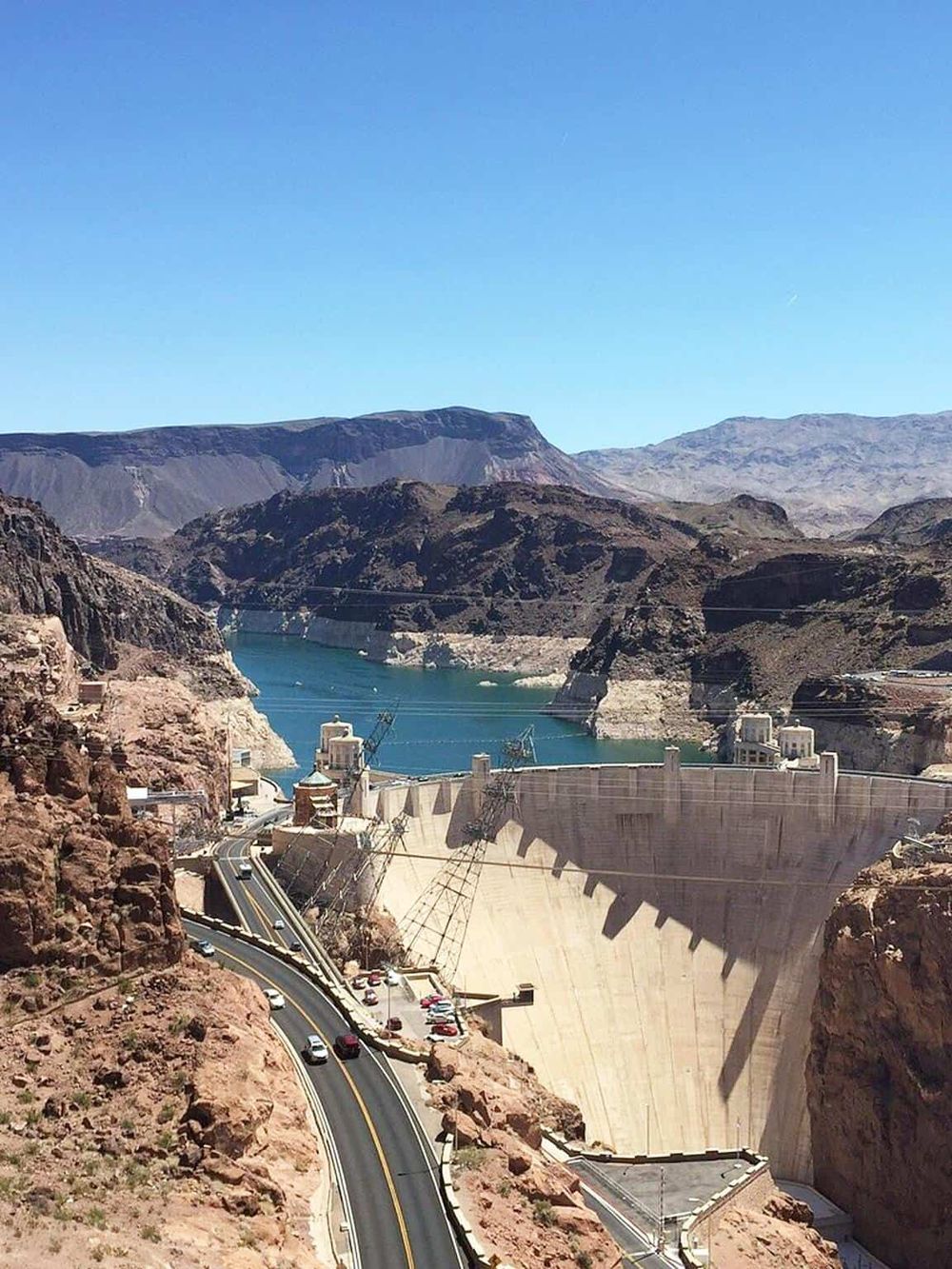 Dam with sprawling landscape and winding road in a scenic canyon.