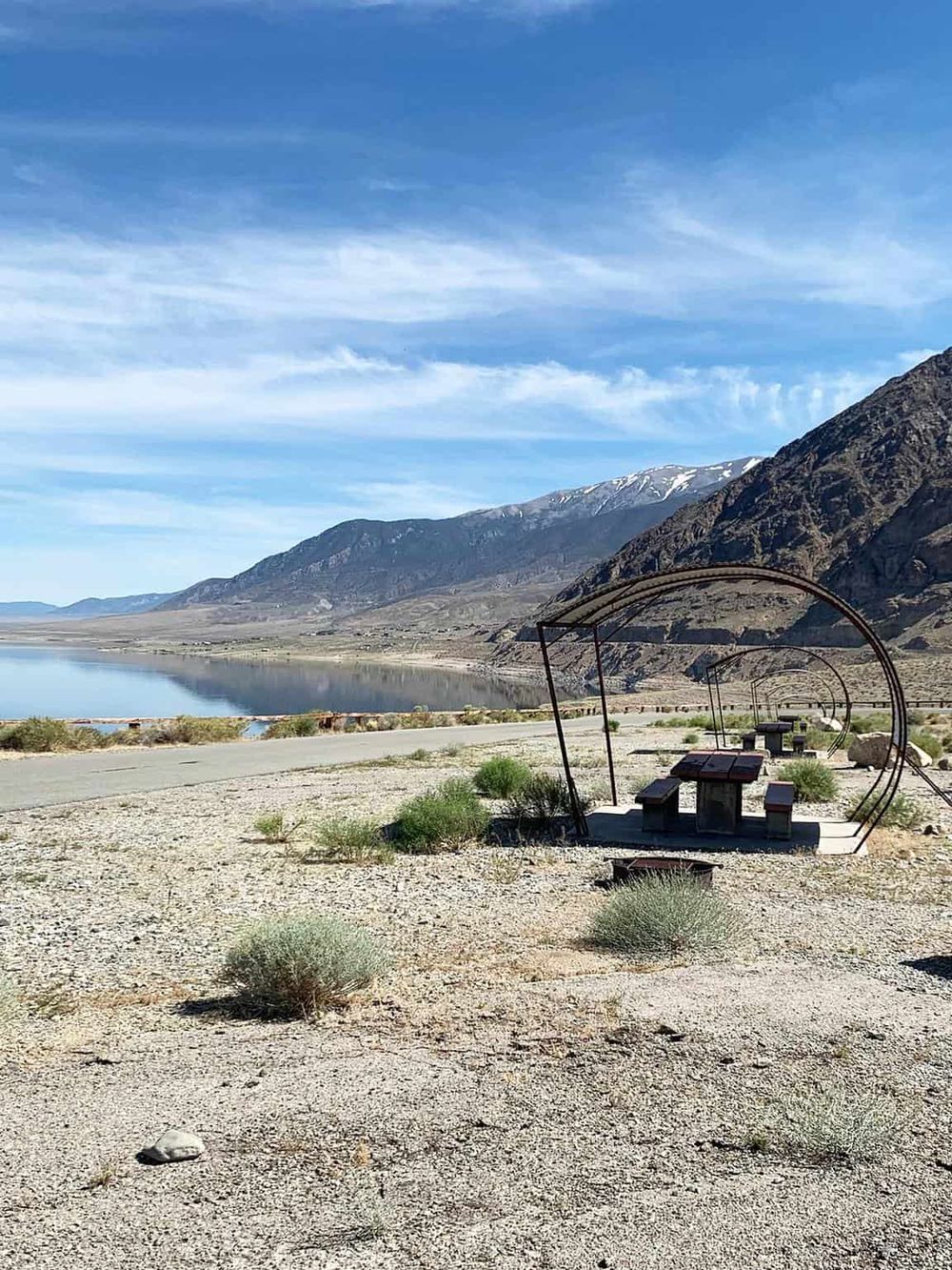 Secluded lake view with benches and mountain backdrop in desert landscape.