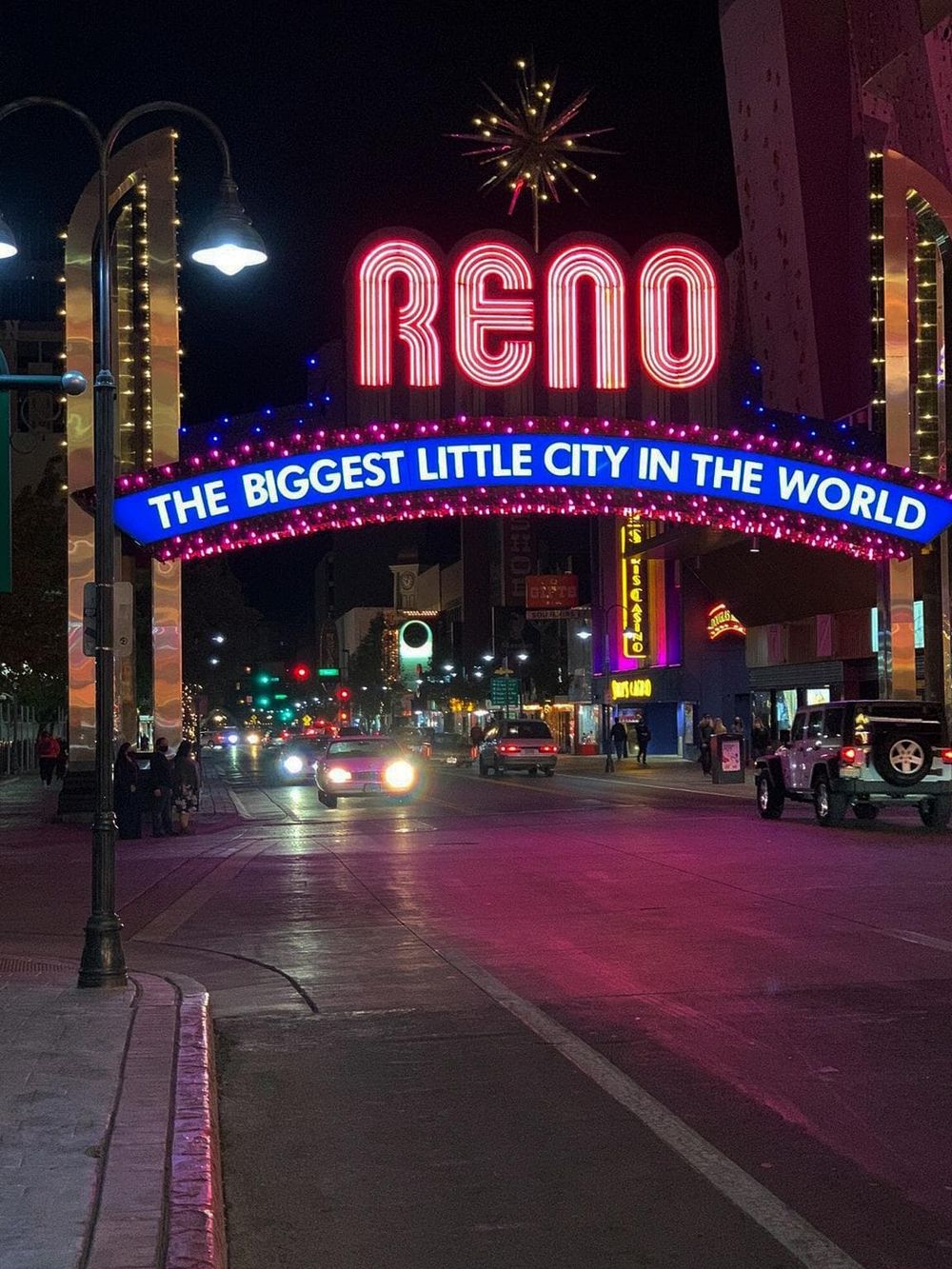 Neon sign reading "RENO" with the text "THE BIGGEST LITTLE CITY IN THE WORLD" illuminated on a bustling city street at night.