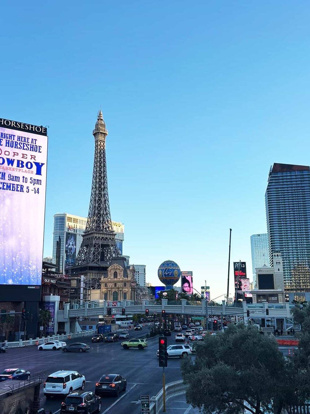 Eiffel Tower replica and Las Vegas skyline with busy traffic and bright digital billboards.