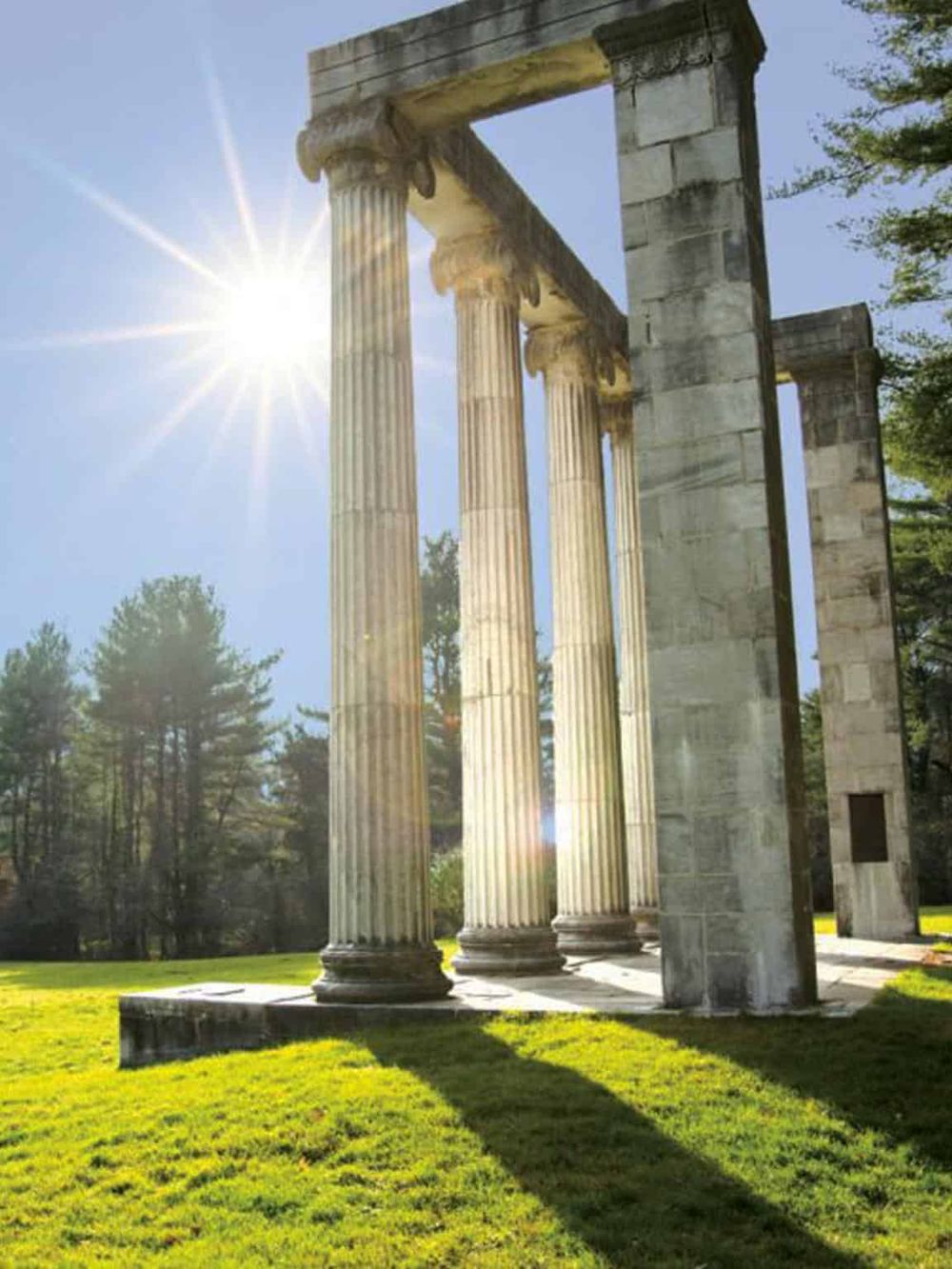 Ancient Greek temple ruins with tall columns illuminated by bright sunlight, scenic outdoor historical site.