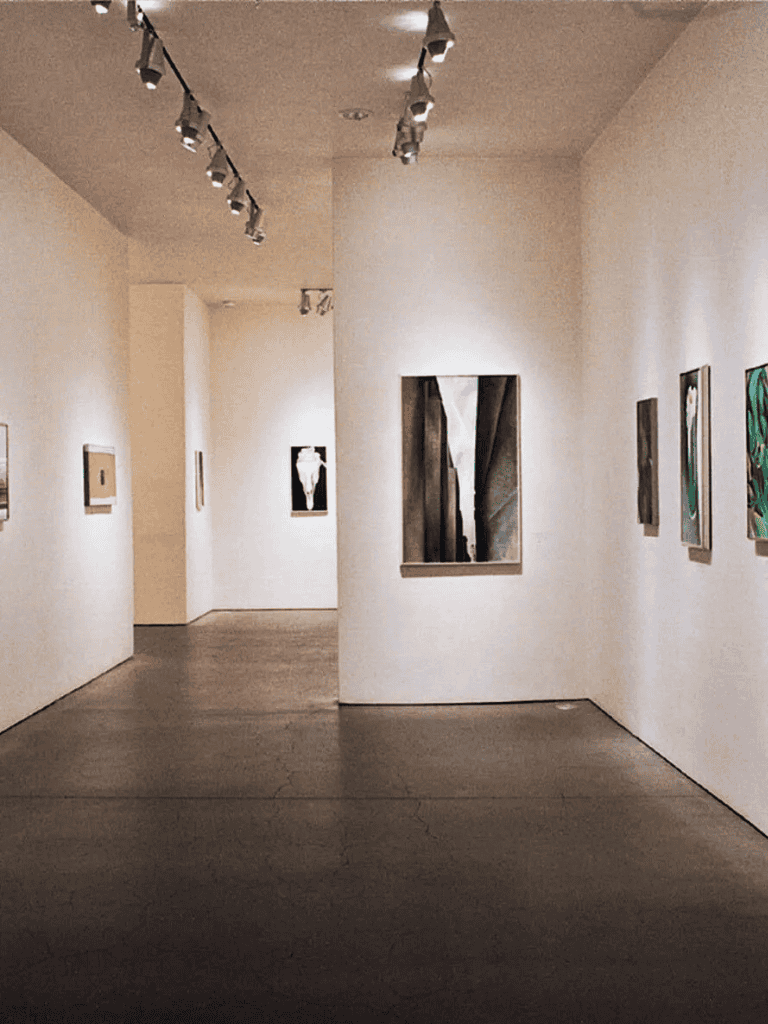 Contemporary art gallery interior showcasing modern paintings and sculptures with spotlight lighting.