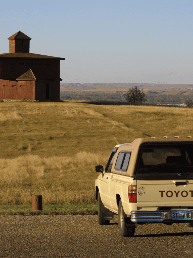 Rustic barn overlooking scenic countryside with classic Toyota truck in foreground.