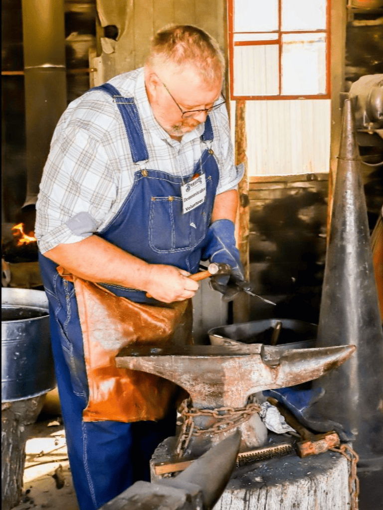 Warm blacksmith working at an anvil in a rustic forge, crafting metal tools with precision and skill.