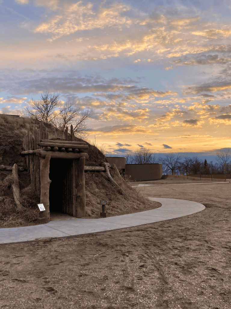 Ancient Native American-inspired structure at sunset, part of QuestForDirections outdoor exhibit.