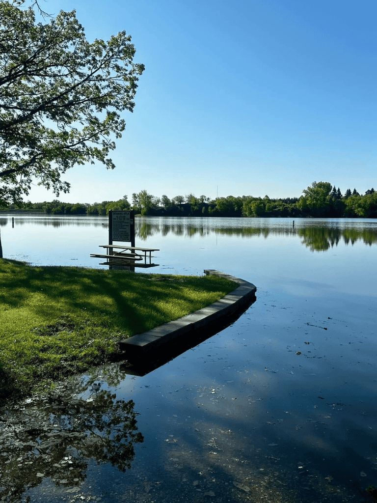 Serene lakeside with dock and lush greenery, perfect for outdoor recreation and nature photography.