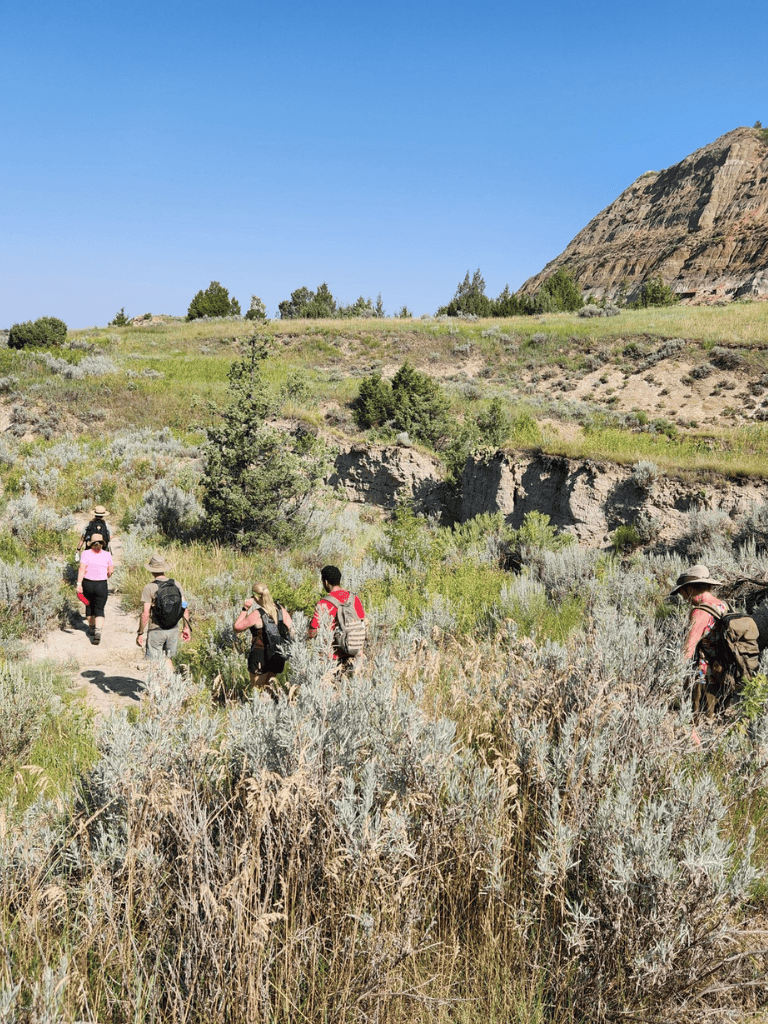 Scenic outdoor hiking trail with a group of hikers surrounded by lush vegetation and mountainous landscape.