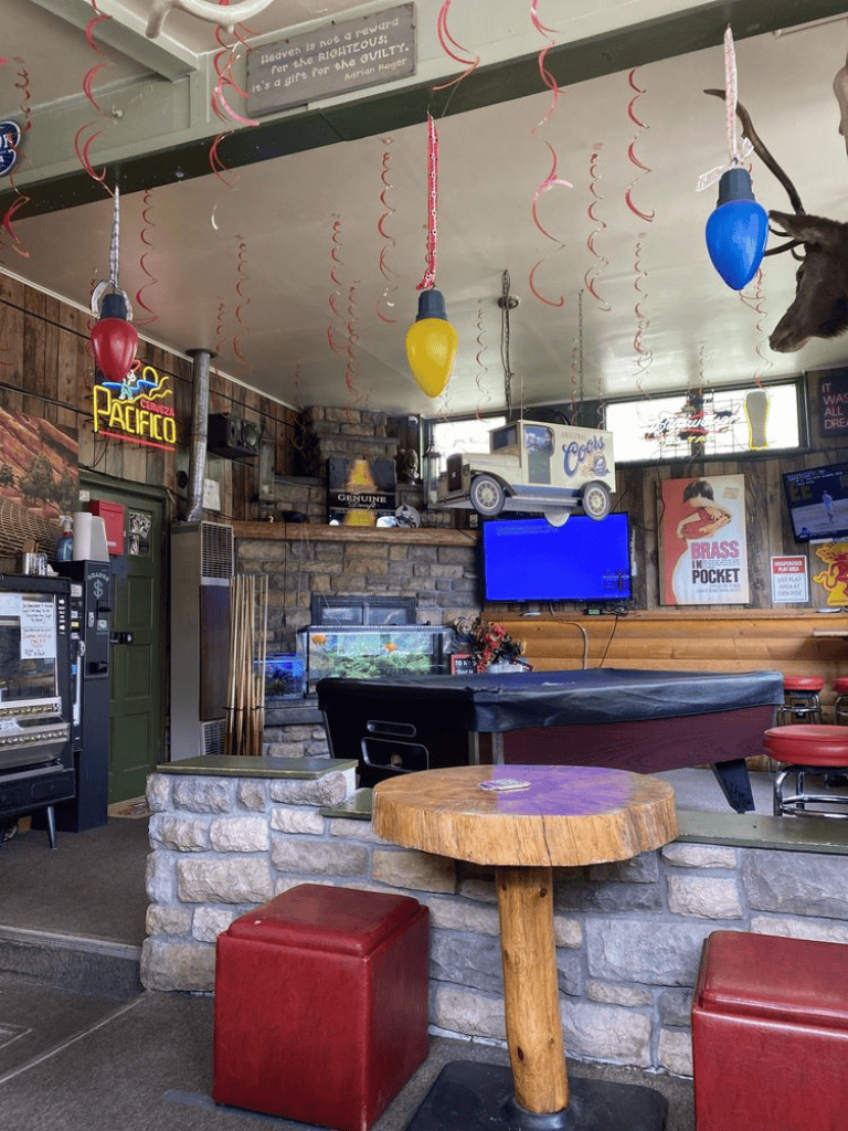 Colorful hanging balloons and festive decor inside a cozy bar and grill with TVs and memorabilia.