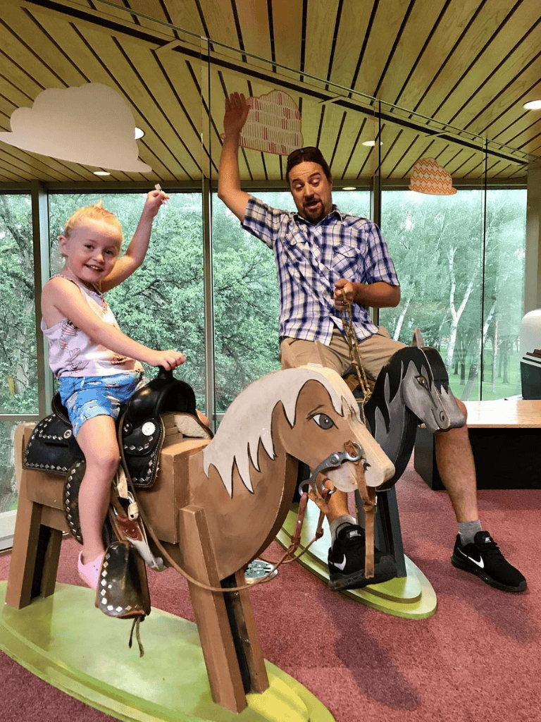 Colorful indoor carousel with children riding horse figurines at QuestForDirections, a family-friendly amusement attraction.