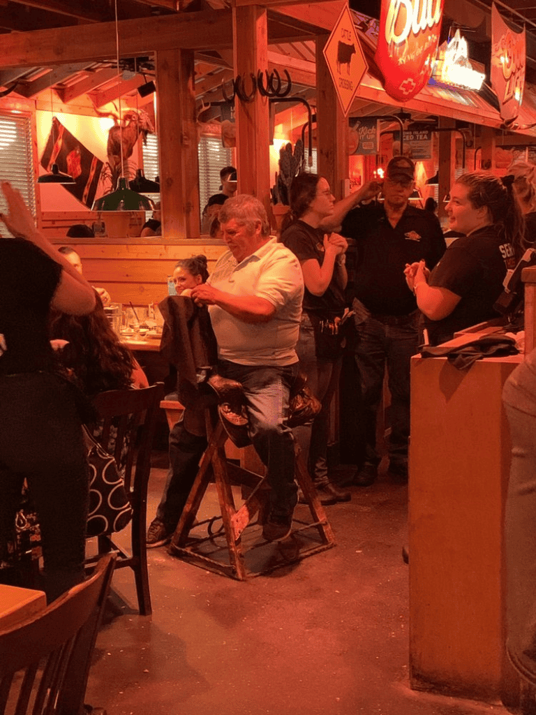 Restaurant social scene with staff and patrons at QuestForDirections. Lively pub atmosphere, warm lighting, wooden décor, and interactors.