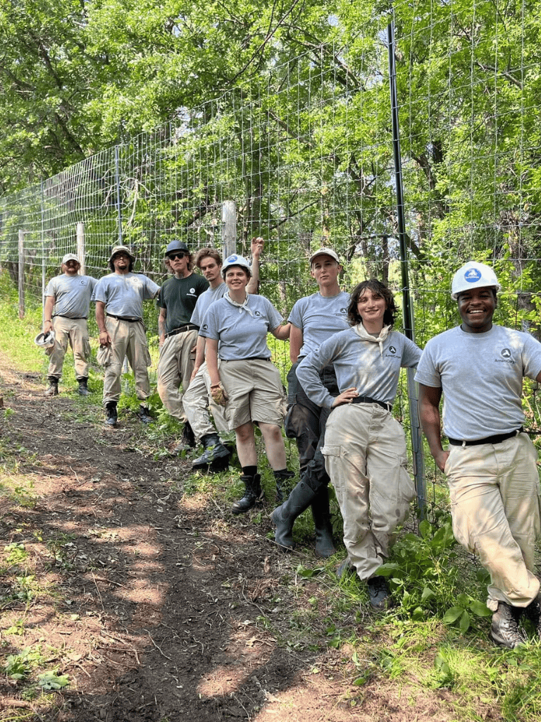 Team of young professionals volunteering for conservation efforts on a wooded outdoor trail, part of QuestForDirections environmental initiatives.