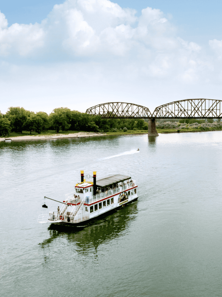 Relaxing river cruise on a scenic boat in Texas with a historic bridge in the background.