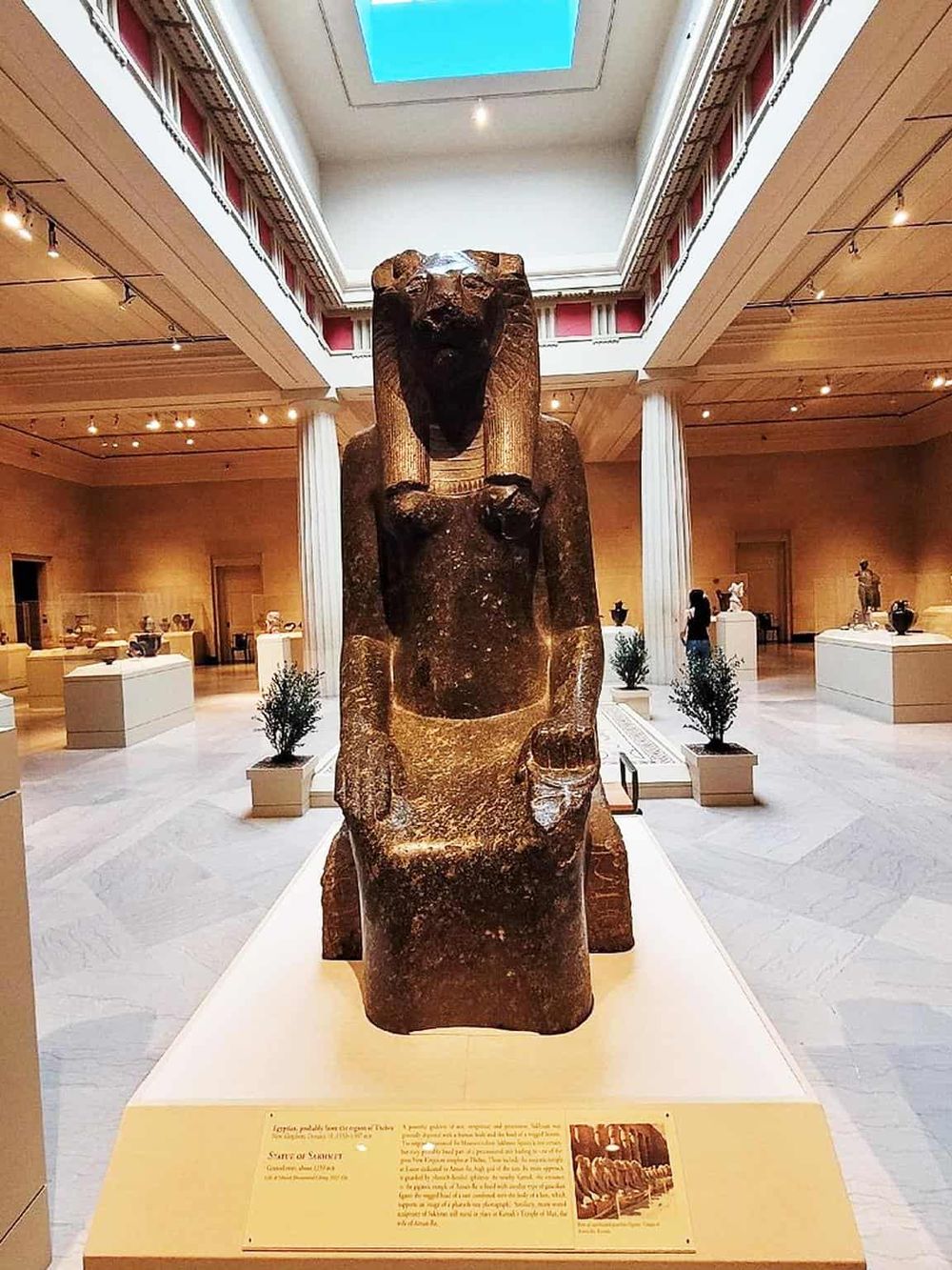 Ancient Egyptian Sphinx statue displayed in a museum gallery with columns and modern lighting.