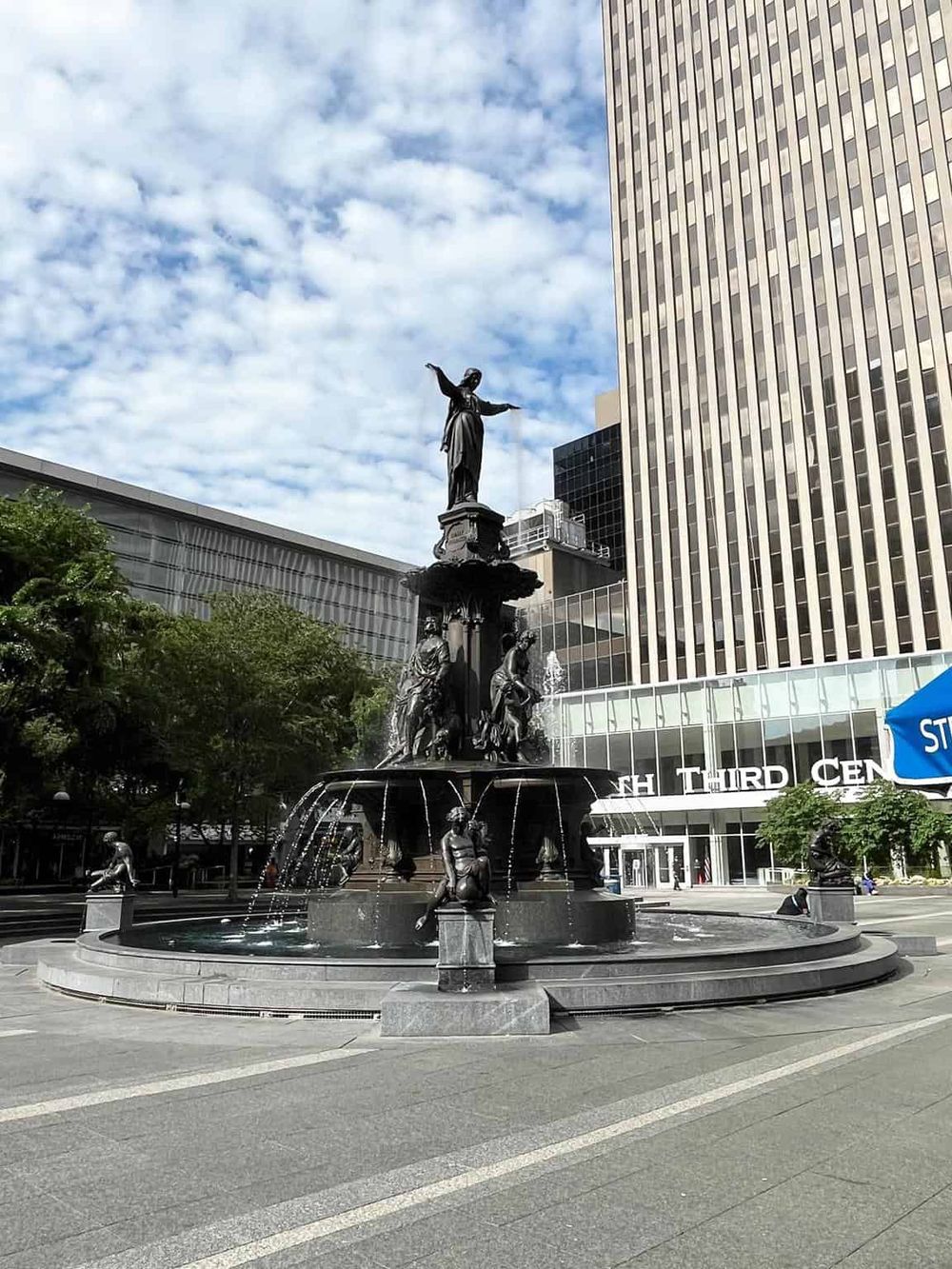 Statue fountain with downtown building background on city street, popular tourist landmark.