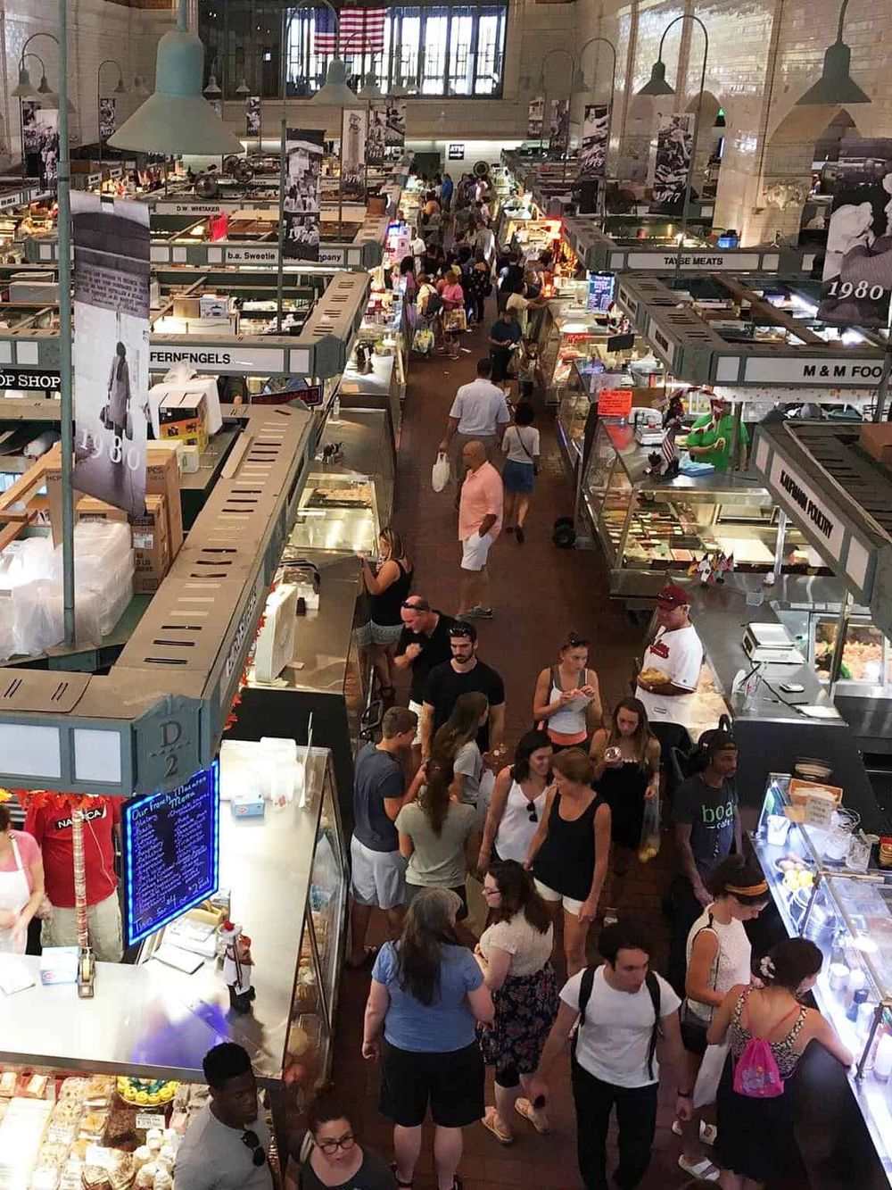 Bustling indoor market with diverse food stalls and shoppers, showcasing a vibrant shopping experience.