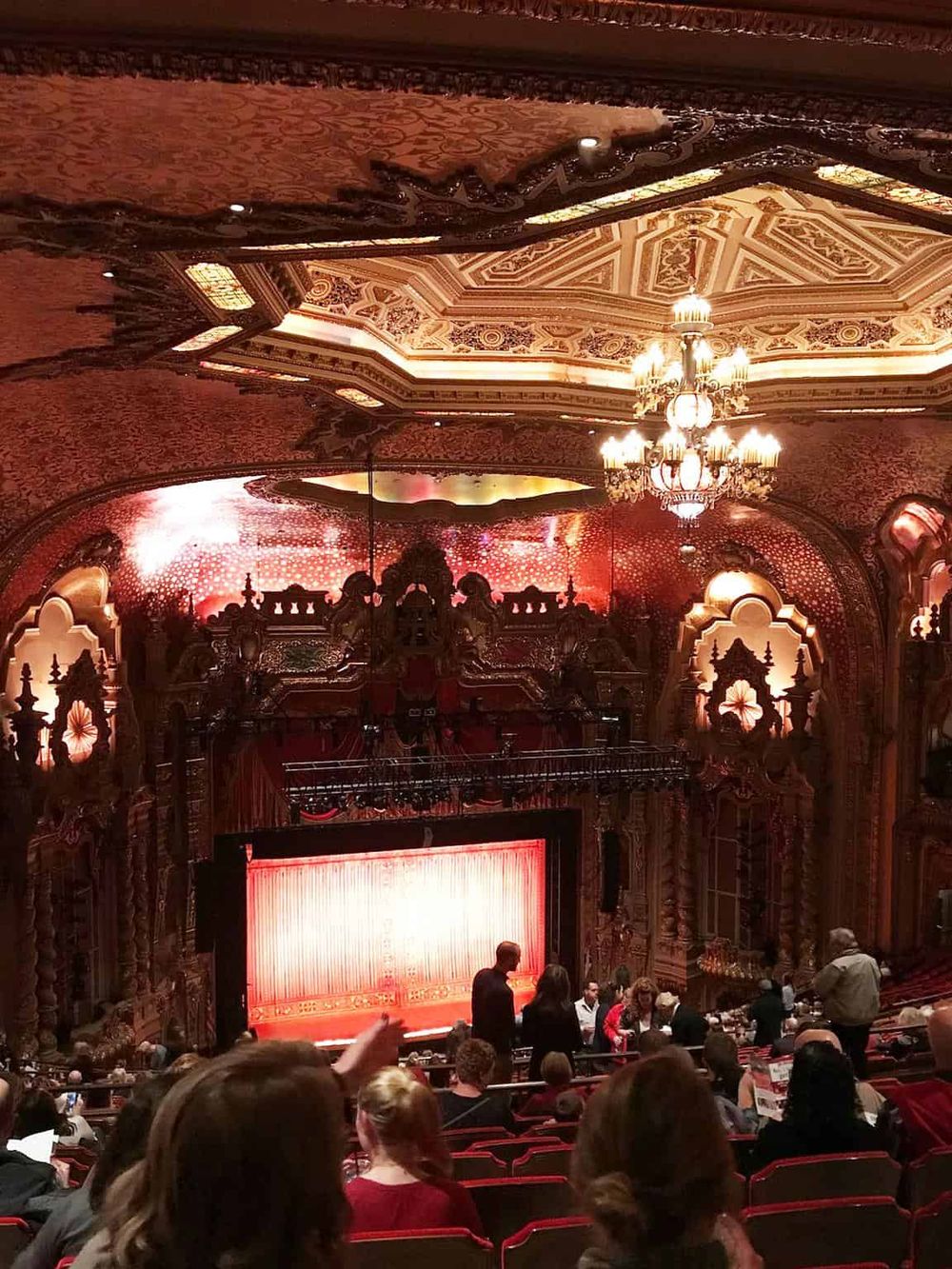 Elegant theater interior showcasing ornate architecture and red velvet seating for a theatrical performance.