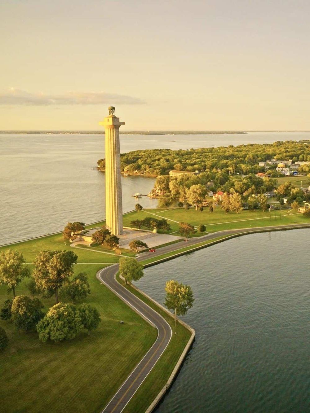 Aerial view of Quest for Directions monument on waterfront with lush greenery and waterway.