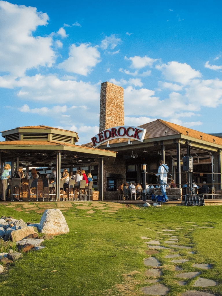 Broad outdoor view of Redrock restaurant with people dining and scenic sky, perfect for travel and dining keywords.