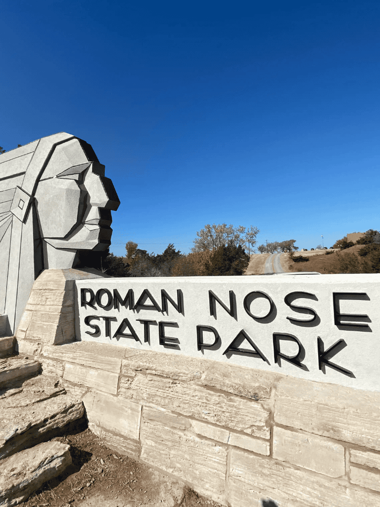 Roman Nose State Park entrance sign with monument, scenic outdoor location, Oklahoma nature, park landmark.