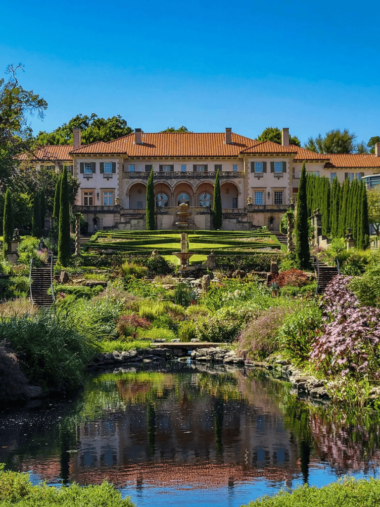 Luxurious mansion with terraced gardens and fountain in scenic landscape.