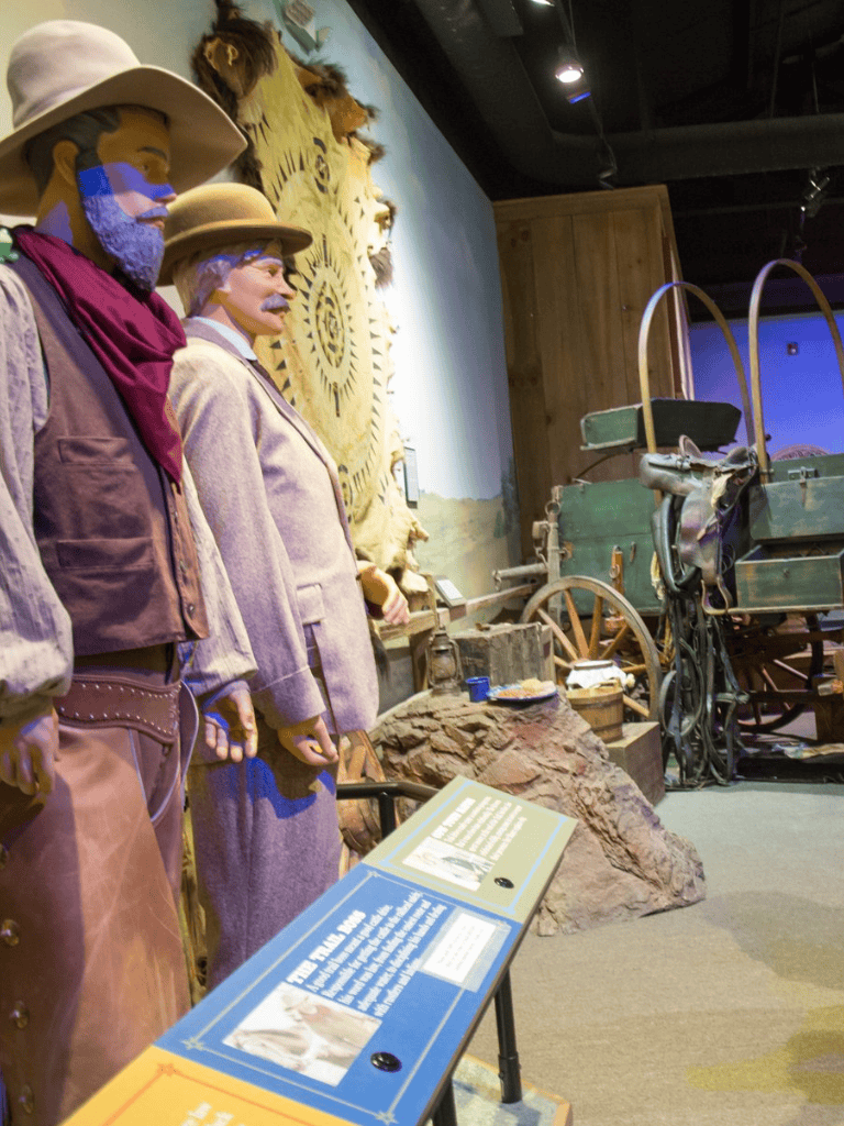 First man with purple beard, second lady with purple beard, third man with purple beard, Old west display with wagon in background.
