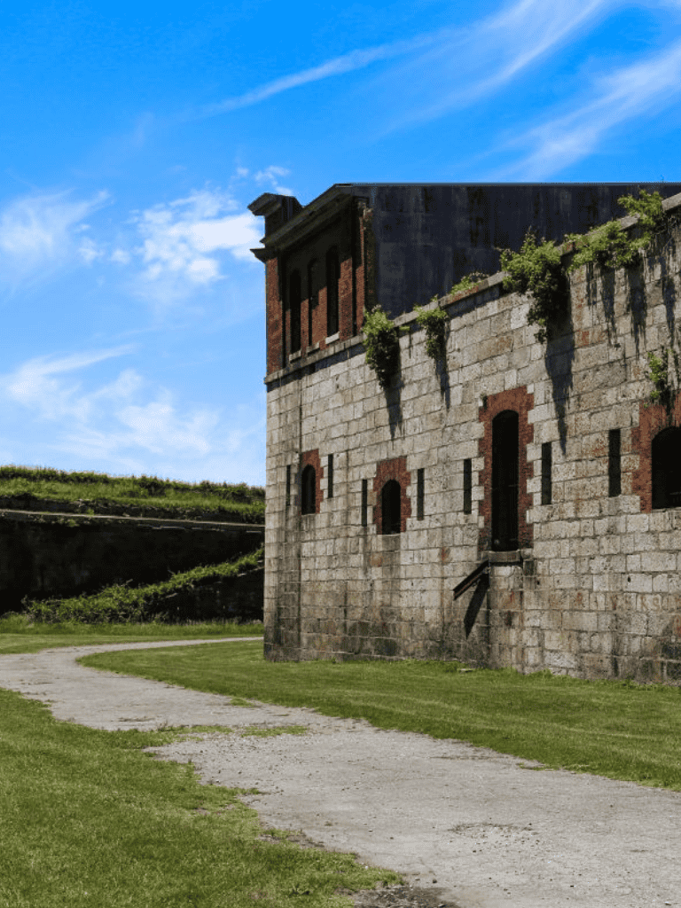 Ancient stone fortress with greenery and blue sky, historic site photography, adventure travel destination.