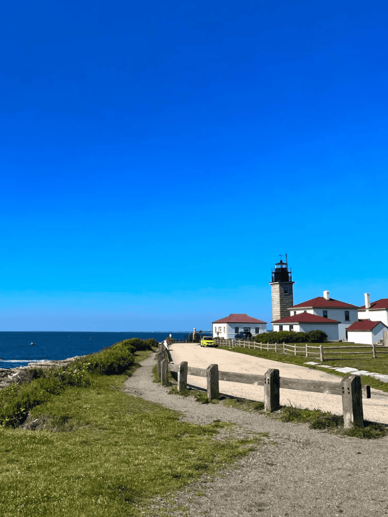 AlT text: Lighthouse and coastal landscape, scenic ocean view with bright blue sky.
