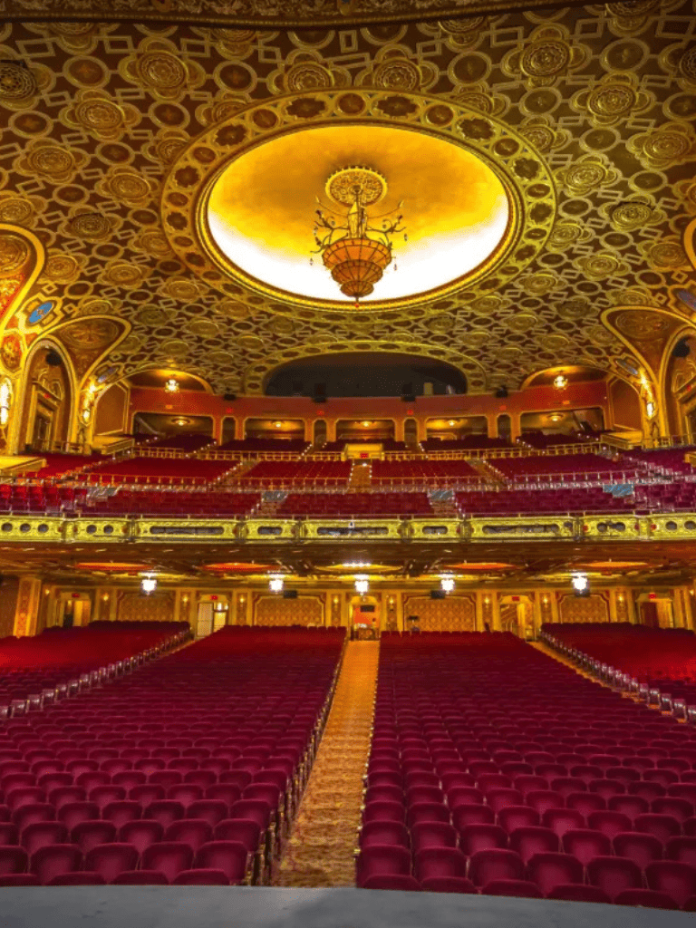 Elegant theater interior with ornate gold accents and plush red seating, perfect for cultural performances and events.