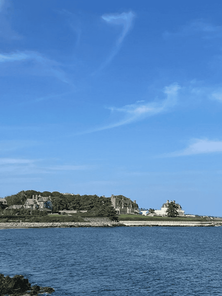 Panoramic view of coastal homes and blue sea under clear sky, scenic waterfront landscape for travel inspiration.