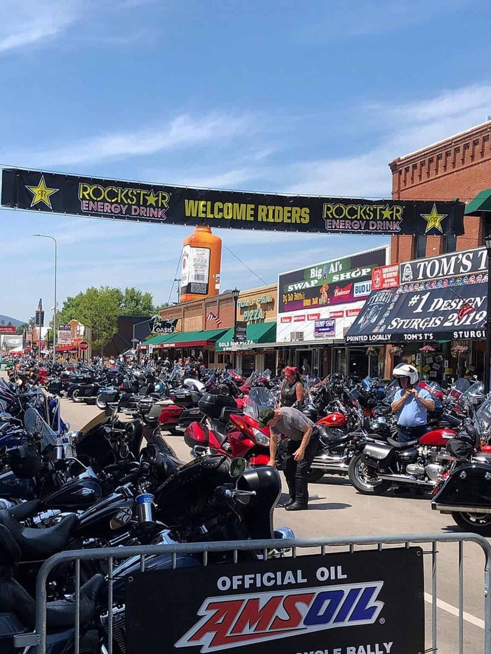 Biker meetup with numerous motorcycles at a lively downtown street event.