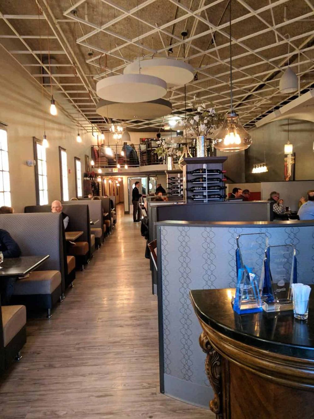 Modern restaurant interior with booths and tables, stylish lighting, and a bustling atmosphere.