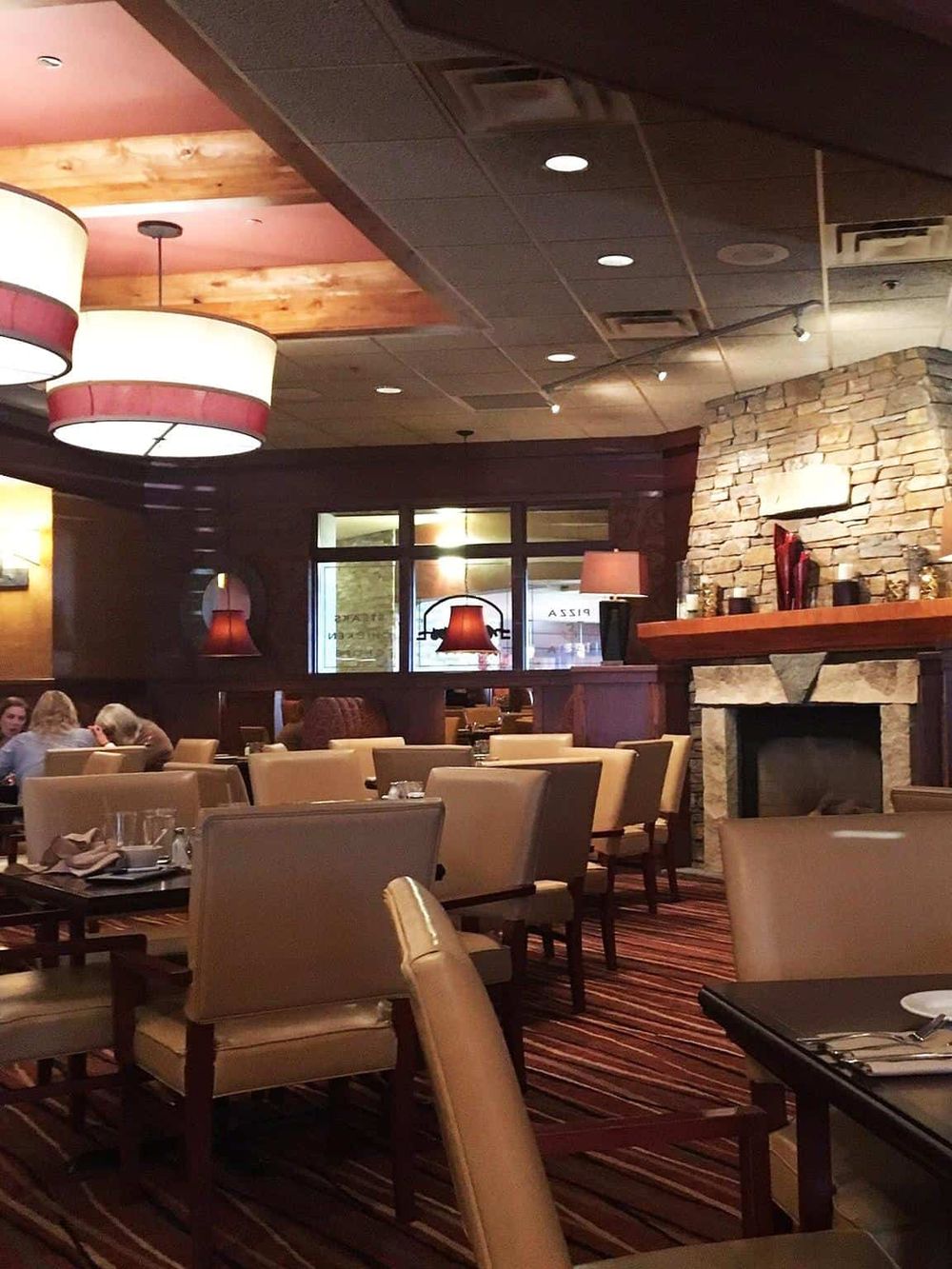 Cozy upscale restaurant interior with warm lighting, stone fireplace, and elegant seating for guests.