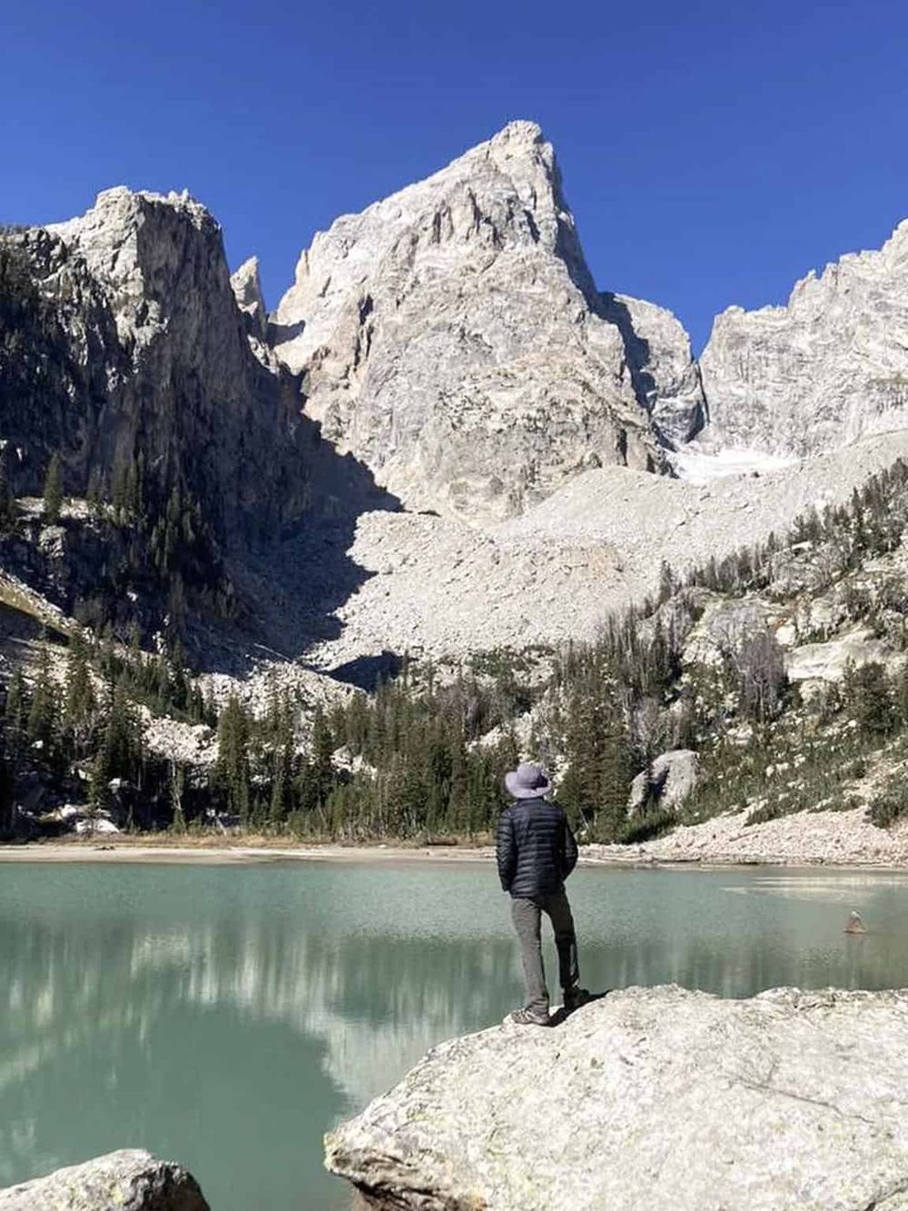 Majestic mountain landscape with a person standing by a serene lake in Yosemite National Park.
