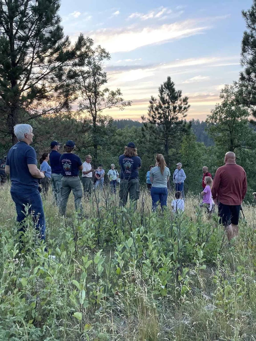 Guided outdoor nature tour with diverse group in forest setting at sunset.