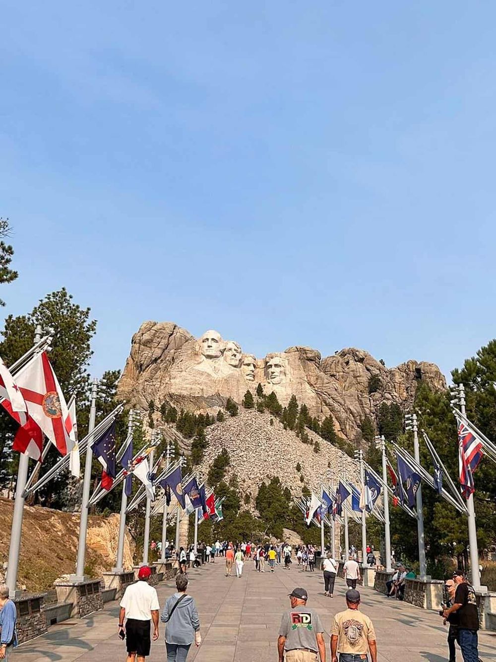Historic Mount Rushmore National Memorial with American flags and visitors in South Dakota.