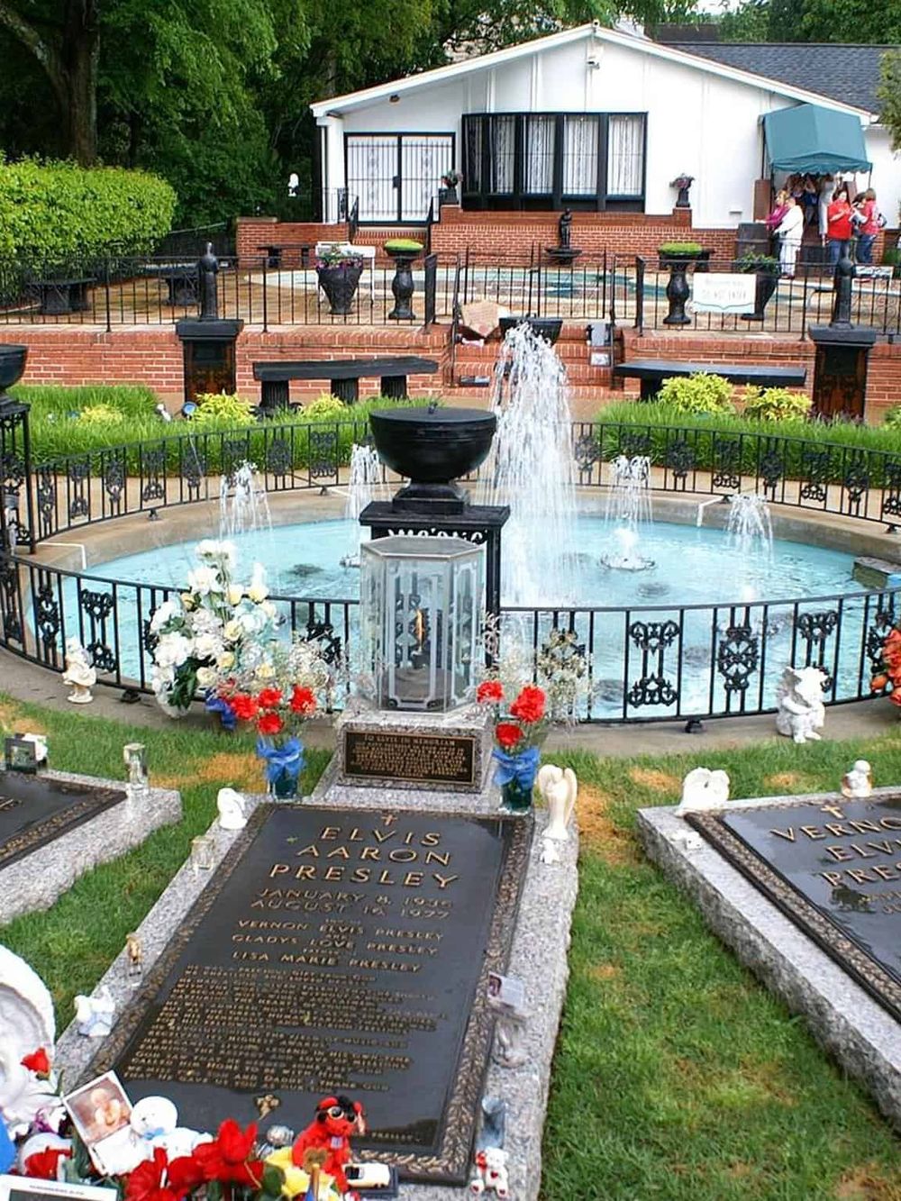 Elvis Presley gravesite at Graceland, iconic Tennessee landmark, with memorial fountain and flowers.