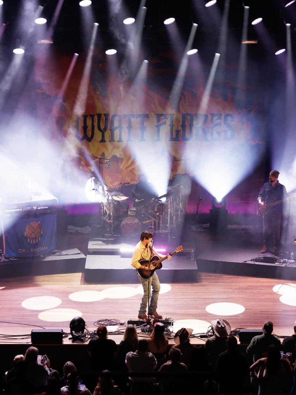 Guitarist performing live on stage at Wyatt Flores concert with vibrant lighting effects.